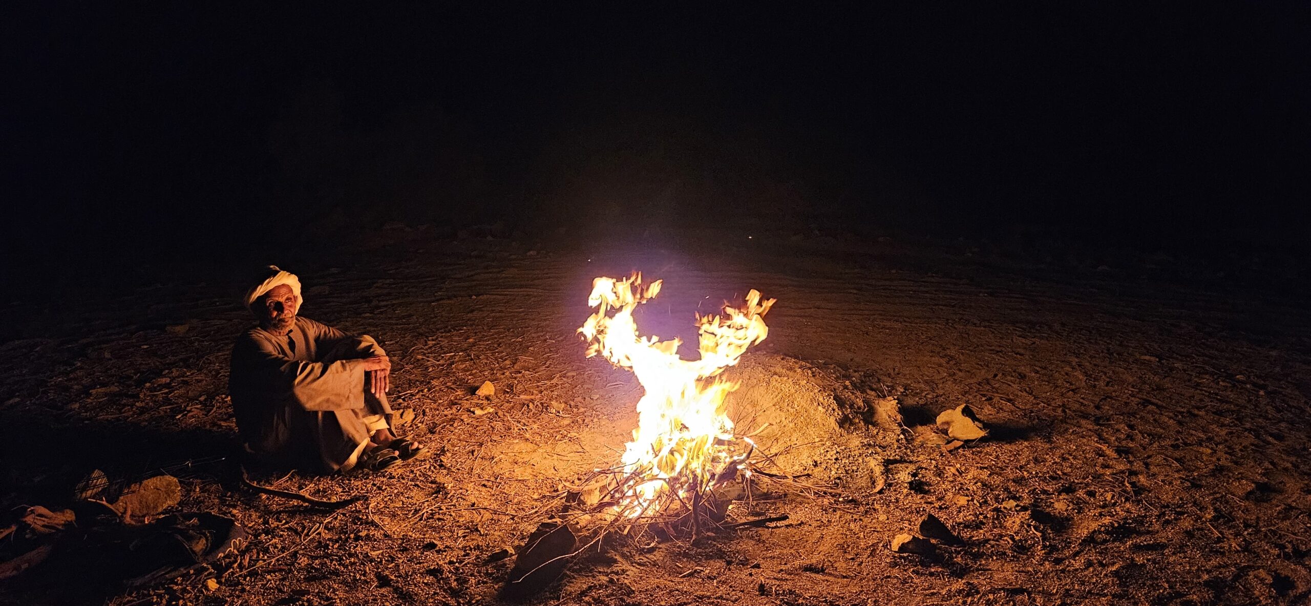 Ababda-Mann nachts an Feuerstelle im Wadi el Gemal, traditionelle Zubereitung von Essen und Tee in der Wüste Ägyptens
