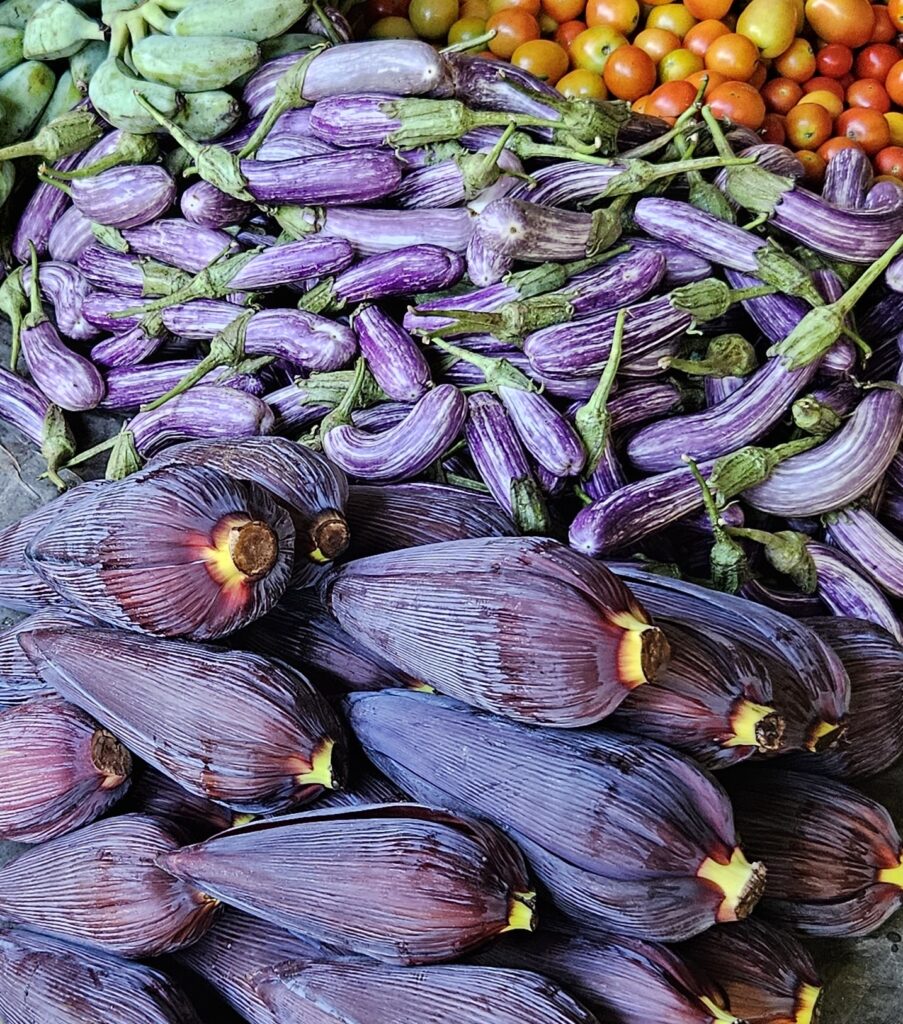 Purple banana blossoms (Musa spp.) and white-and-purple eggplants (Solanum melongena) at a market in Sri Lanka