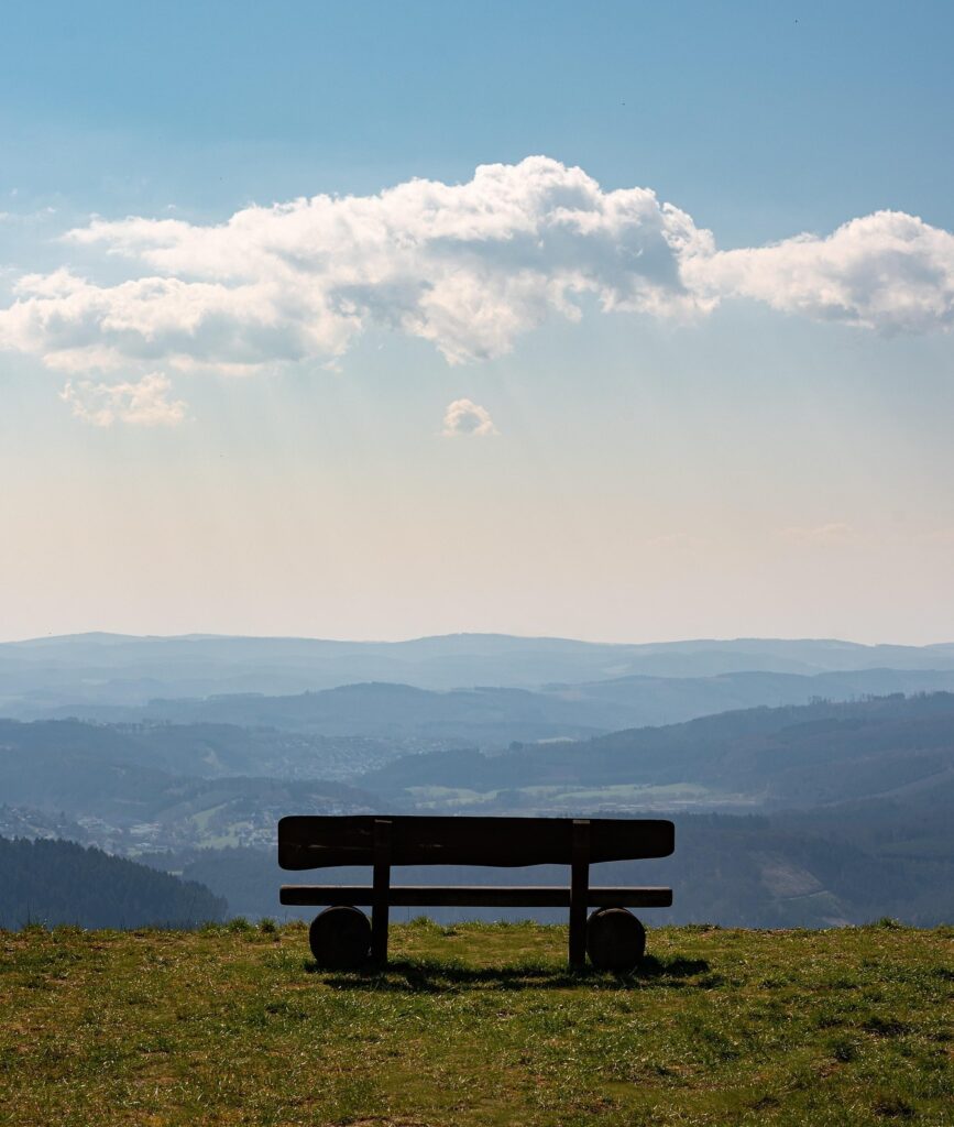Holzbank auf Hügel mit Blick über weite Landschaft